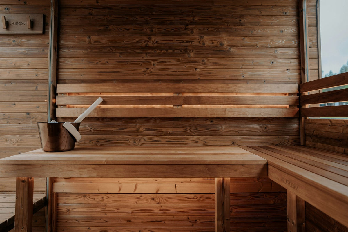 Wooden sauna bench with a bucket and ladle against cedar walls