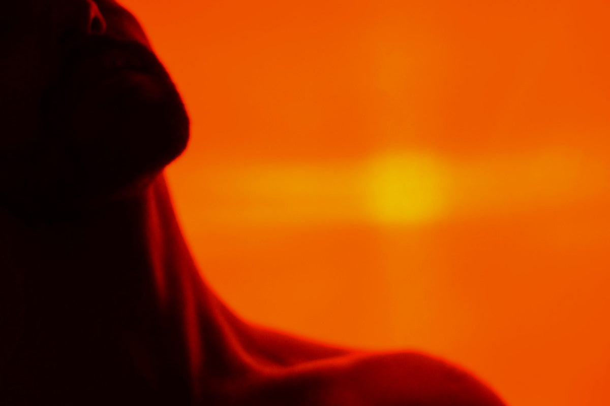 Silhouette of a person's neck and shoulder against a deep orange glow