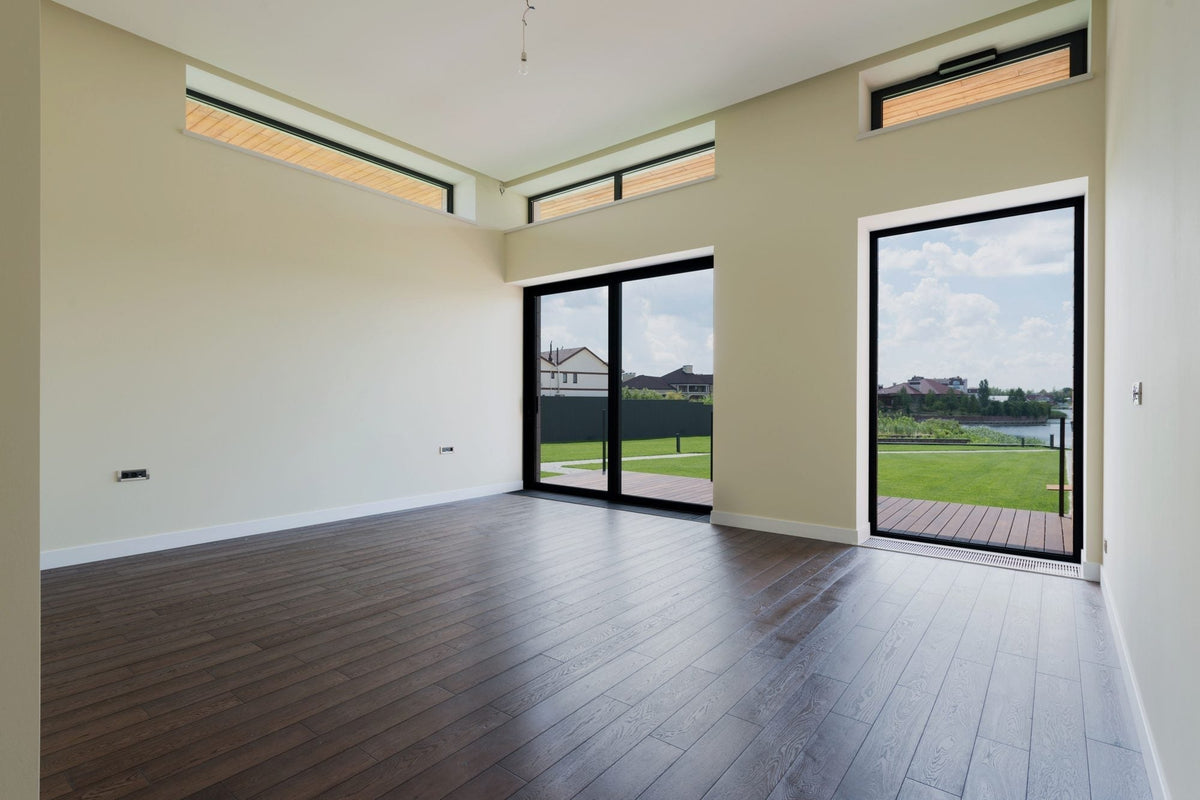 Empty bright room with large glass doors opening to a lawn