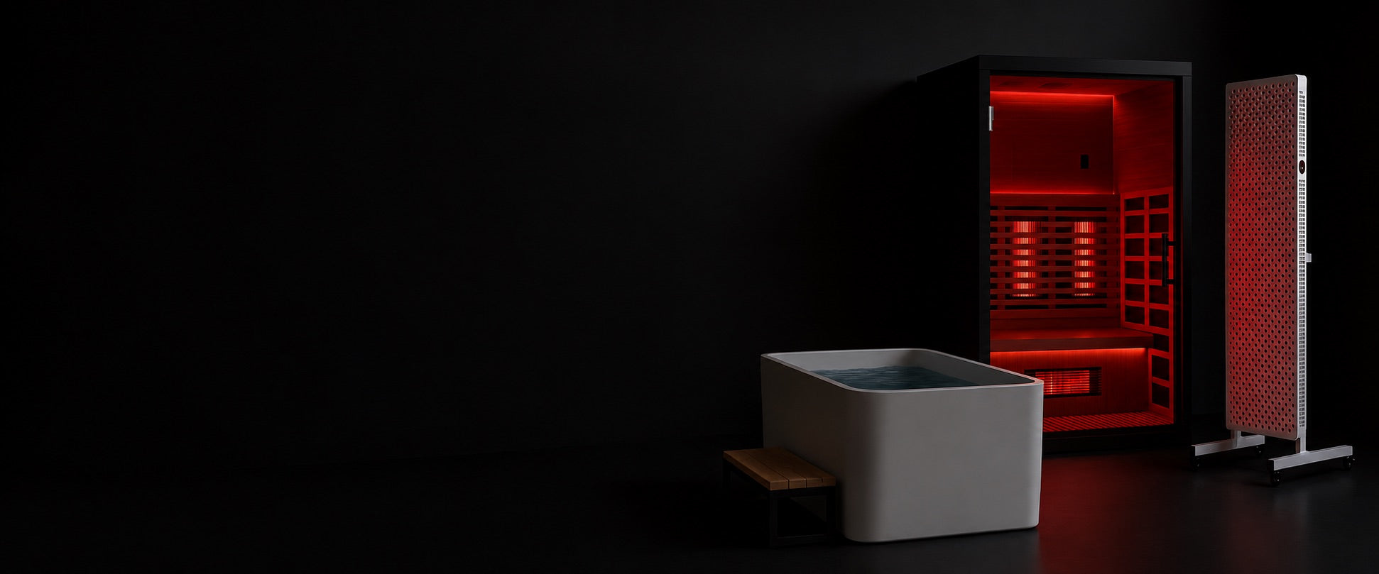 Infrared sauna, cold plunge tub, and red light panel in a dark recovery room